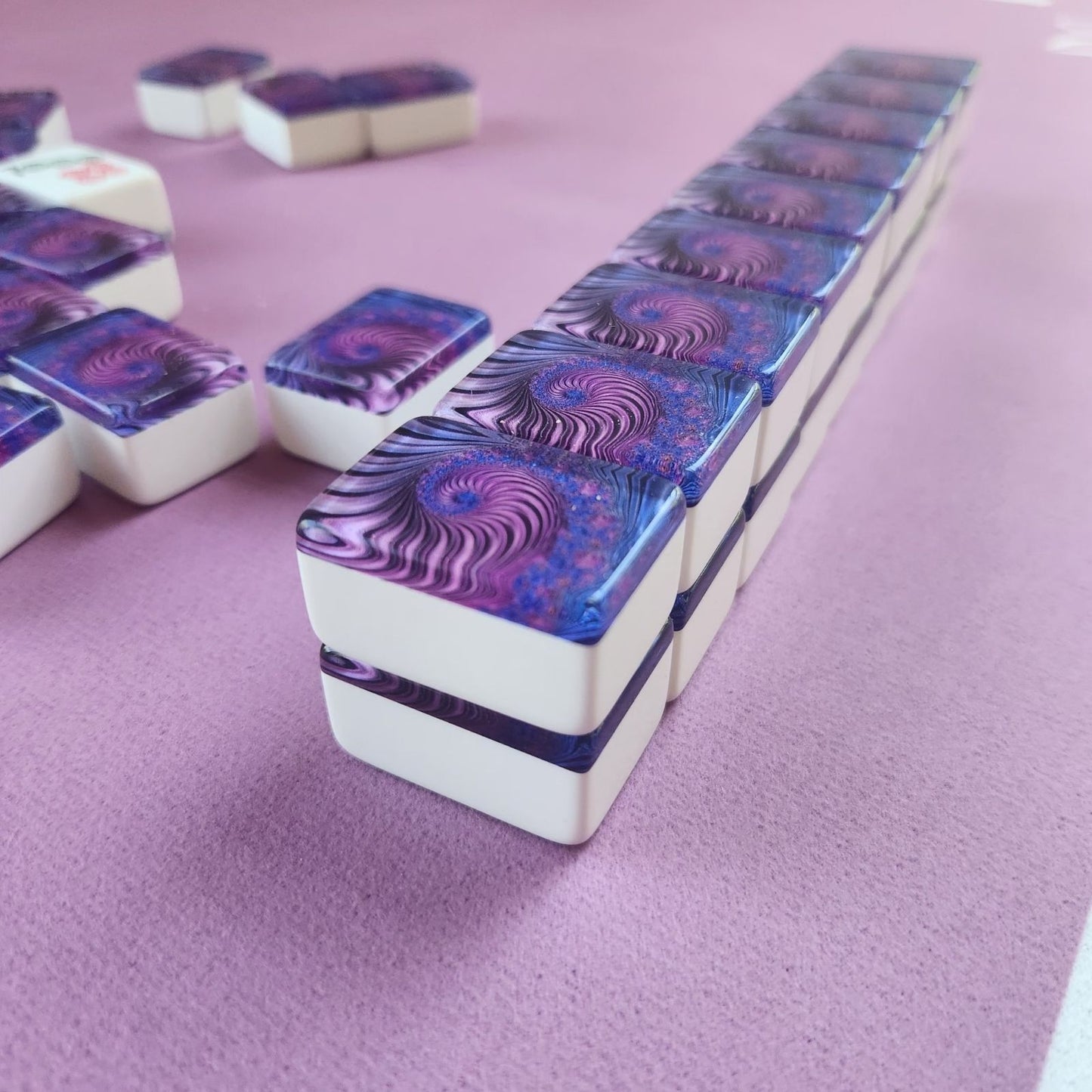 A set of white rectangular cards with glossy purple and blue psychedelic swirl patterns on the top, arranged on a lavender surface.