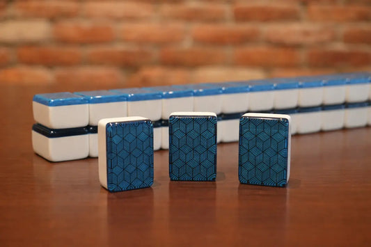 Three standing mahjong tiles showing a blue 3D cube geometric pattern in front of a matching stack.