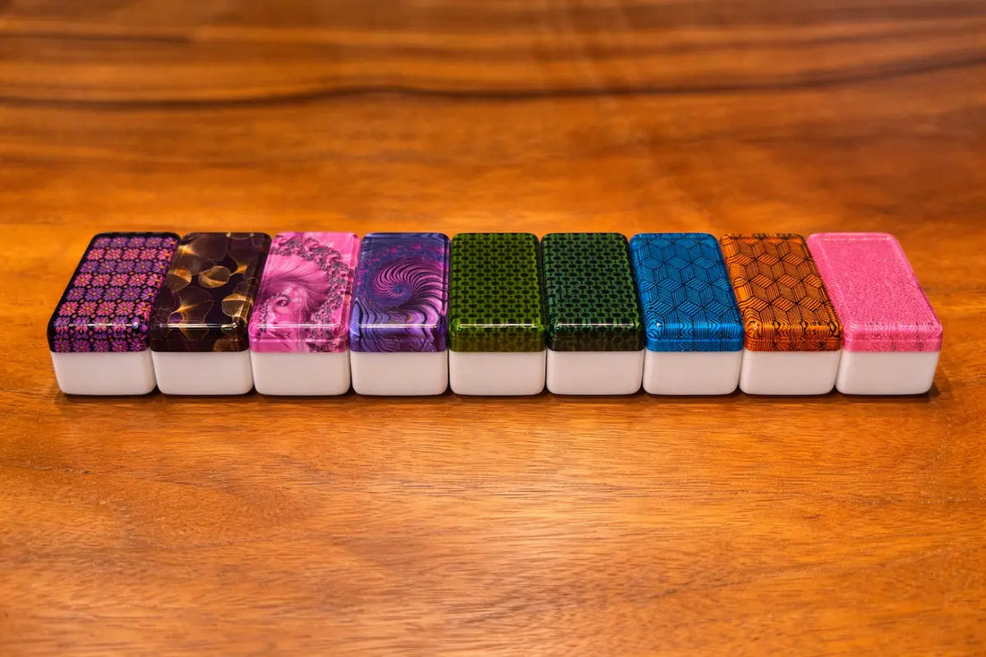 A row of nine mahjong tiles showing various artistic backs including floral, geometric, and fractal designs.