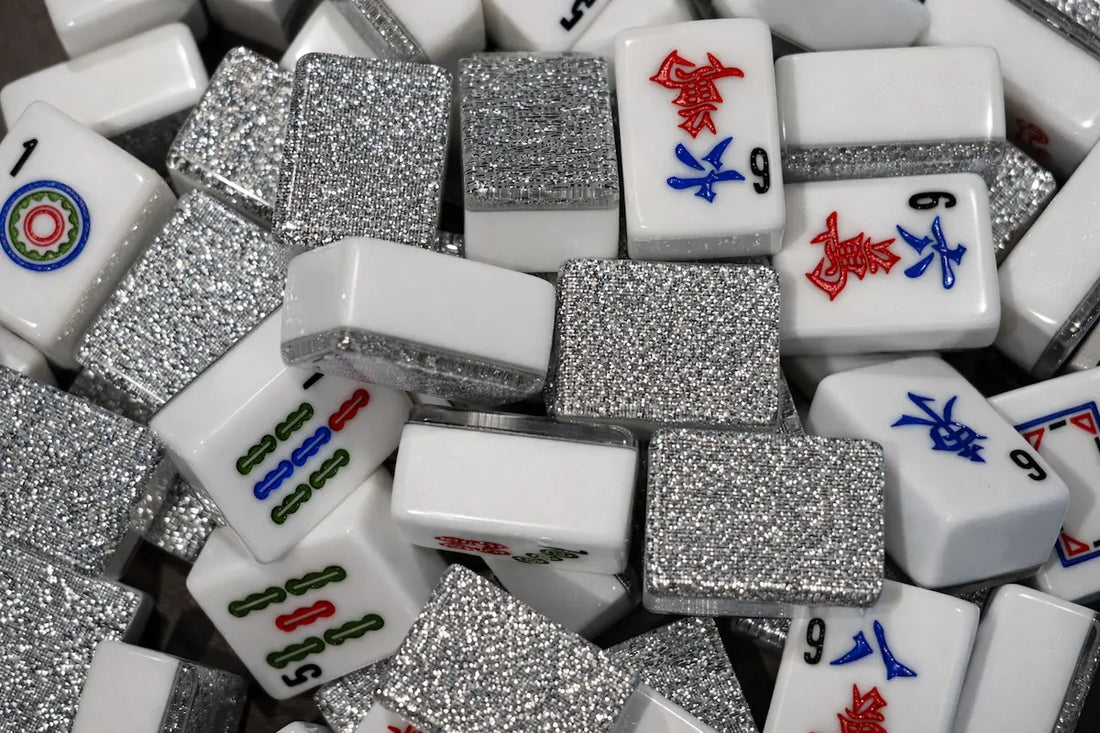 A dense pile of white mahjong tiles with high-intensity silver glitter backs and blue and red engravings.