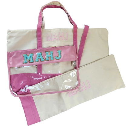 Canvas tote bag with Mahjong branding with pink accents and straps against white background