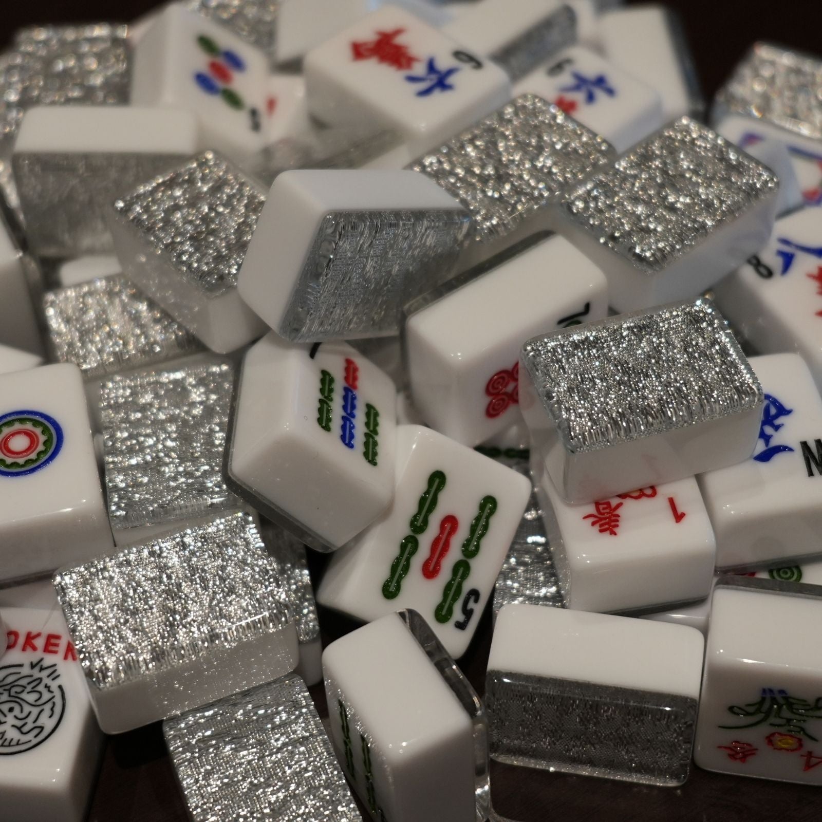 Close-up of a pile of white Mahjong tiles with silver glittery accents.