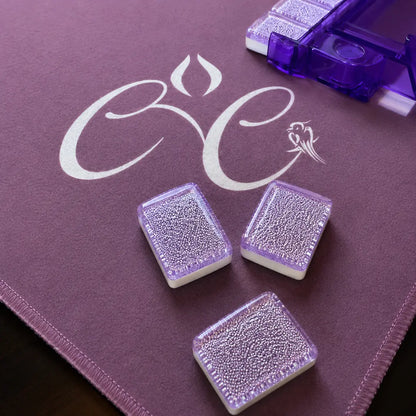 Three purple Mahjong tiles on a purple surface with a logo.