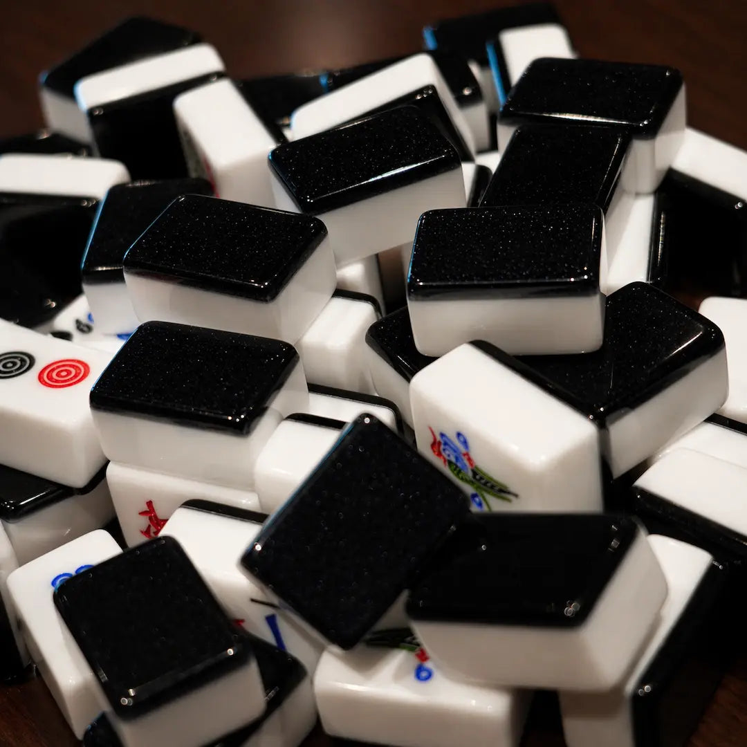 Pile of black automatic Mah Jongg tiles scattered on a wooden table