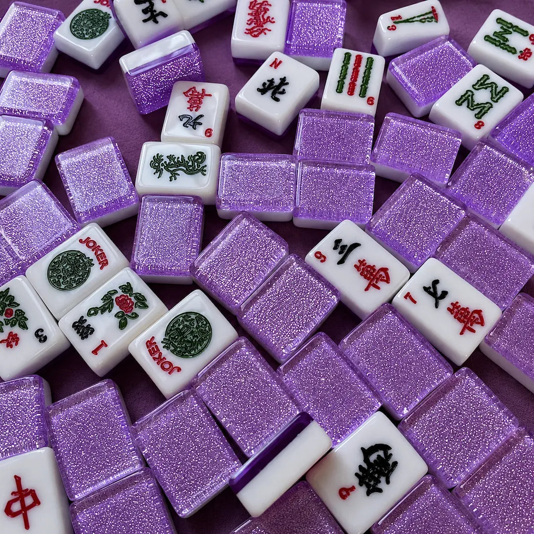 Purple sparkle American Mah Jongg tiles scattered on purple felt
