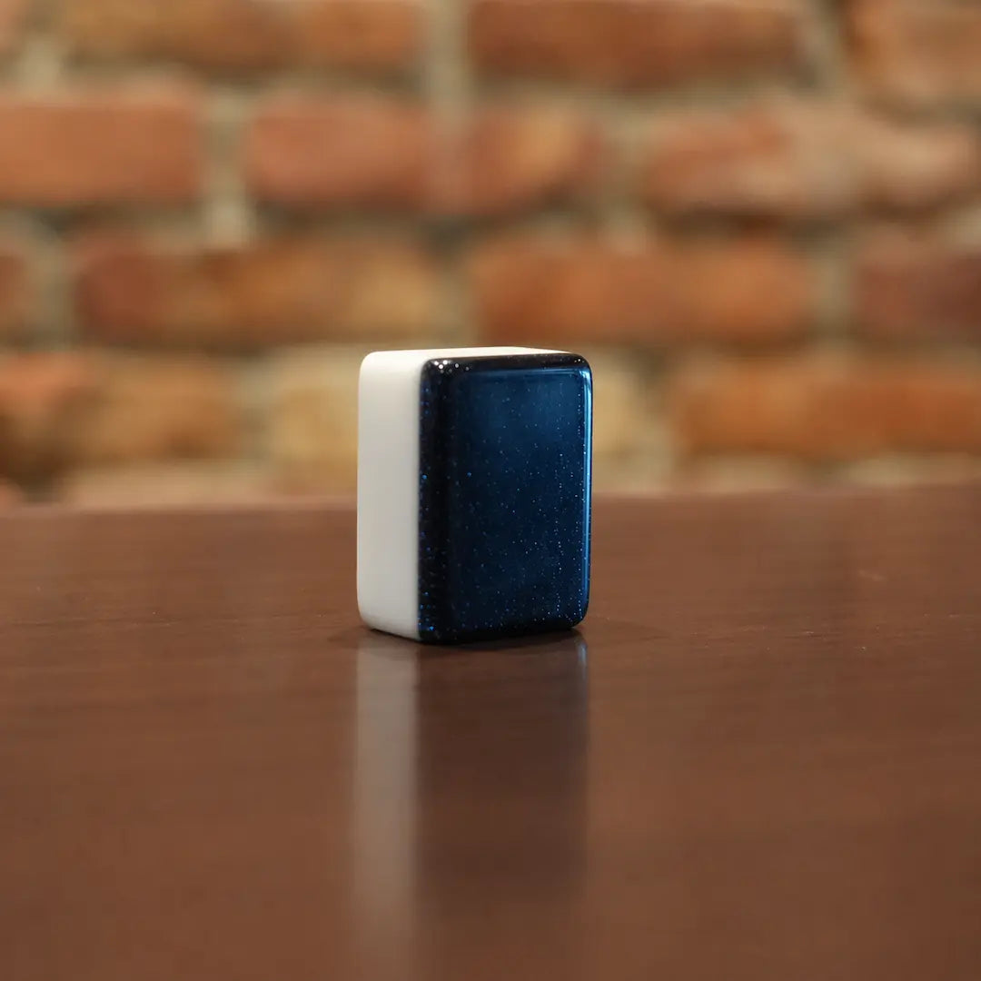 Single black automatic Mah Jongg tile on a wooden table