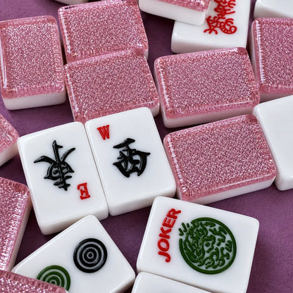 Close-up of pink and white Sparkling Mahjong tiles with various symbols on a purple background