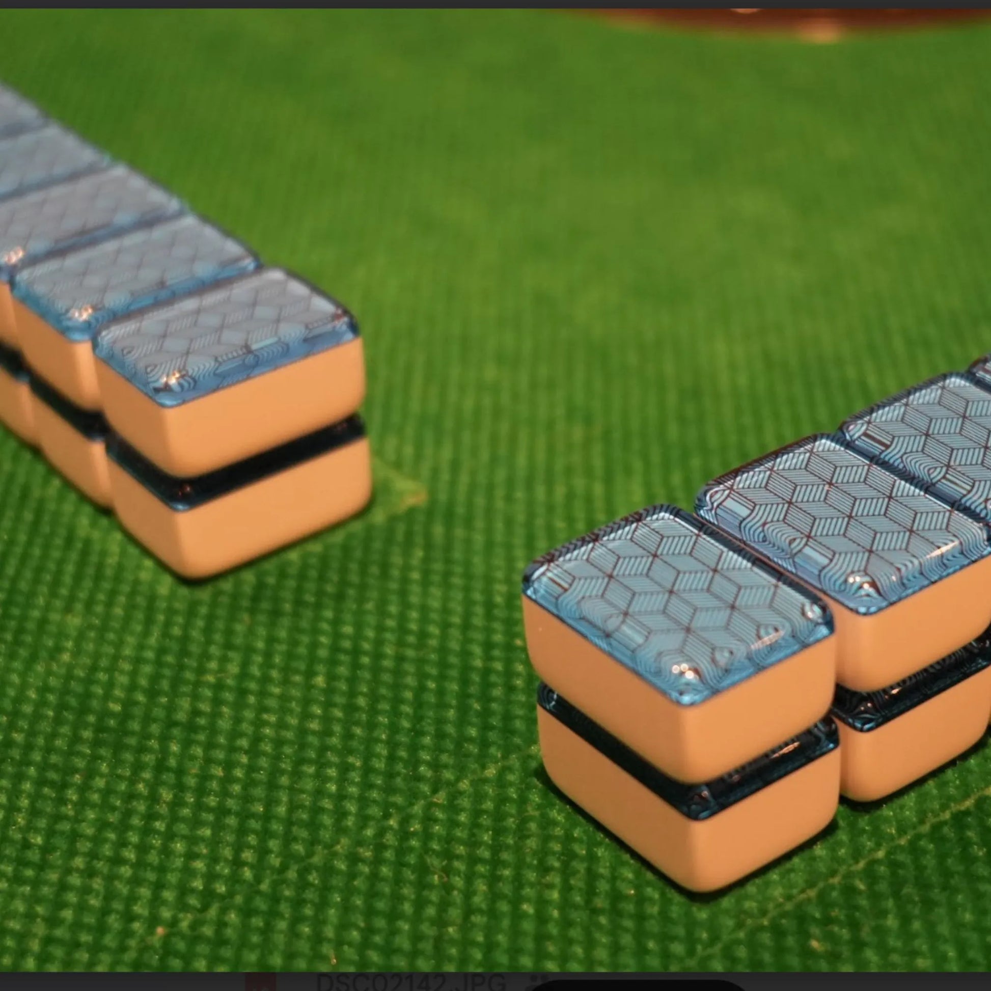 Two walls of 36mm blue deco weave automatic mah jongg tiles set up for play on a green mat.