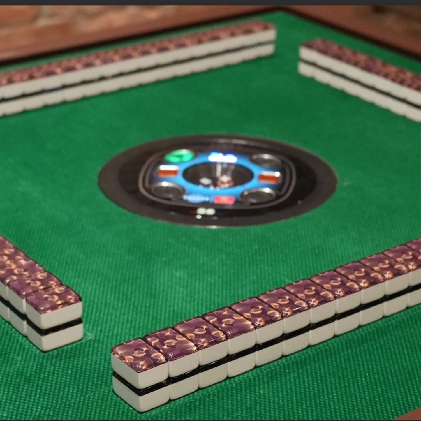 Full view of an automatic mah jongg table with gingo tiles arranged in four walls on a green mat ready for play.