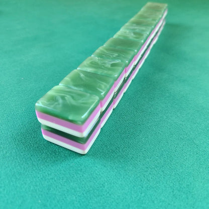 A set of green marbled mahjong tiles stacked diagonally on a green felt surface.