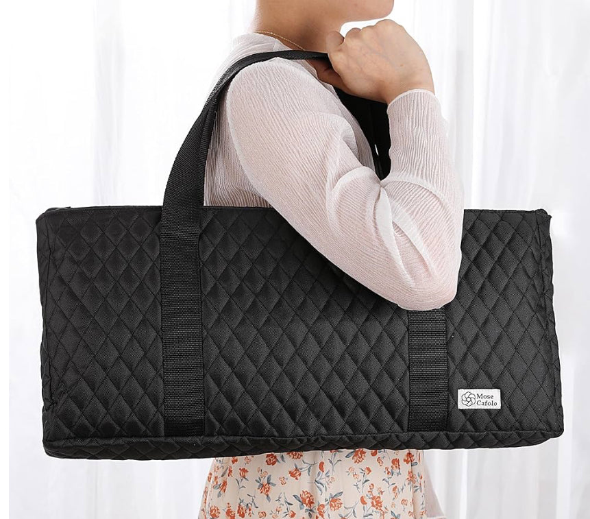 Person holding a black quilted bag with a visible brand logo against a white background