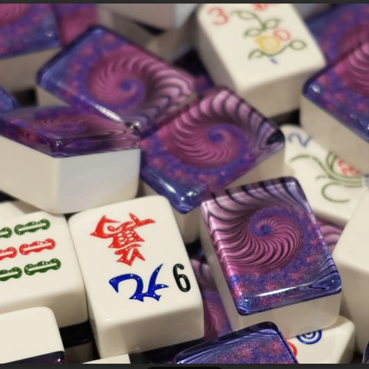 Mixed pile of 36mm automatic mah jongg tiles in purple swirl design showing white engraved faces and purple backs.
