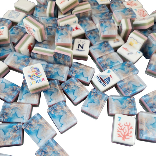 A pile of decorative mahjong-style tiles with a blue and white marbled pattern, scattered on a white background. Some tiles show traditional Chinese characters, and a few have illustrated faces including a joker and a coral 7.