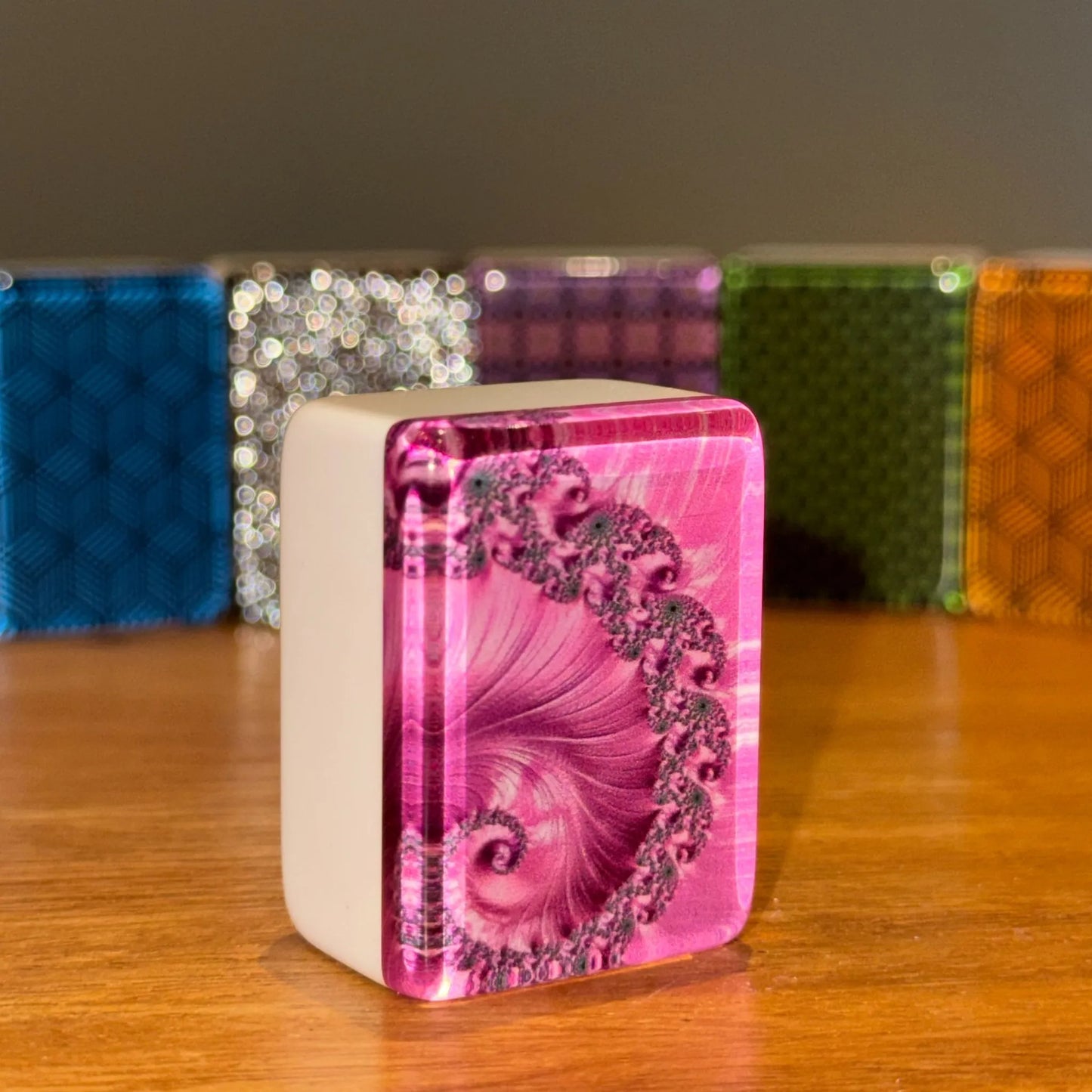Close up view of a single pink swirl mah jongg tile standing upright to show the intricate spiral back pattern.