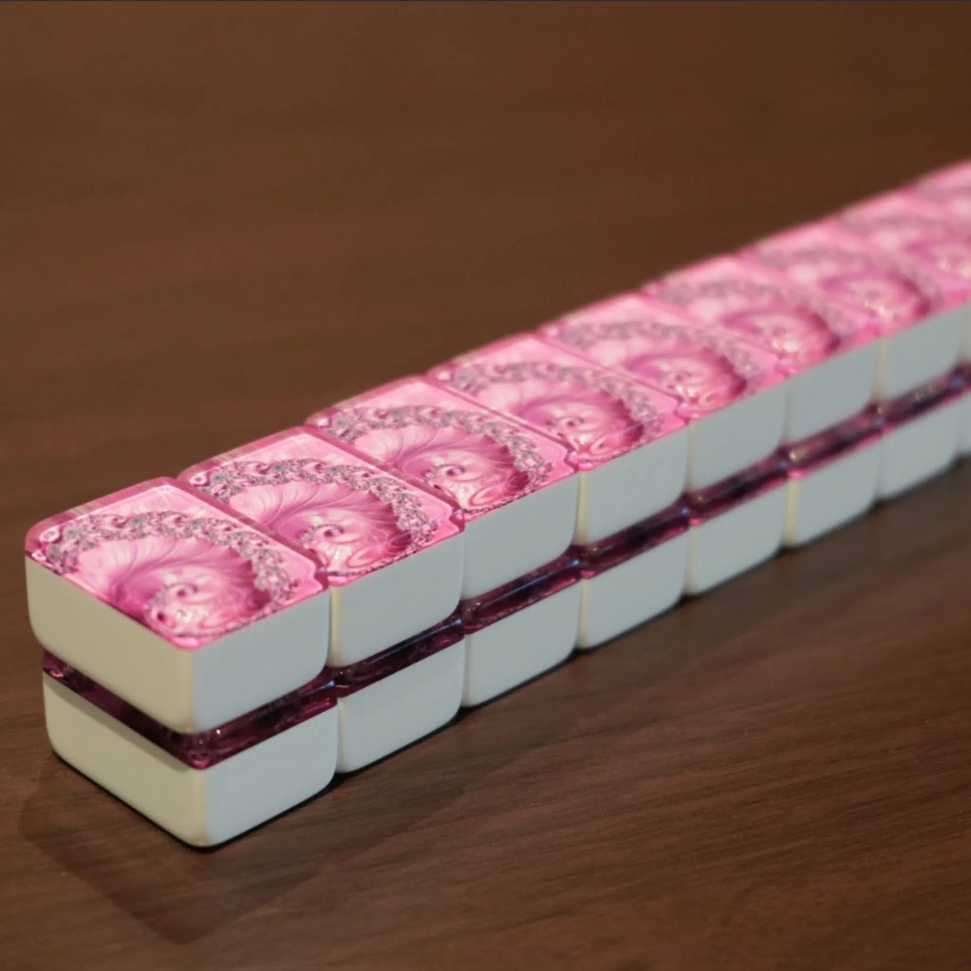 Angled view of a full double-stacked wall of 36mm pink swirl automatic mah jongg tiles ready for play on a wooden table.