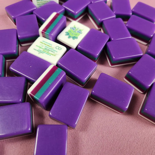 Purple game tiles with a few colorful tiles on a pink surface