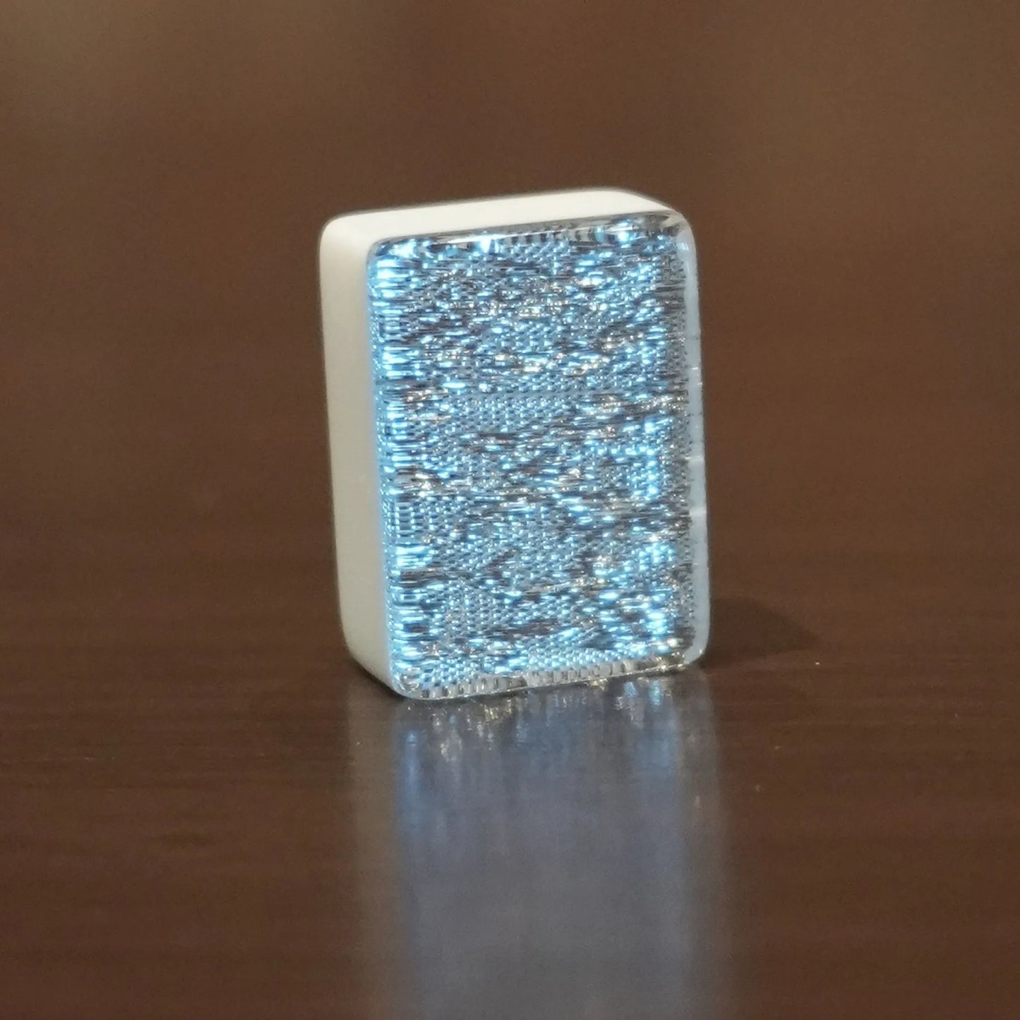 Single silver sparkle 36mm automatic mahjong tile with glitter face on wooden surface
