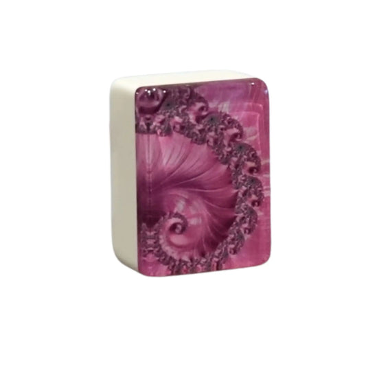 Close up view of a single pink swirl mah jongg tile standing upright to show the intricate spiral back pattern.