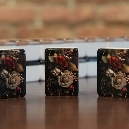 Three standing rose pattern mah jongg tiles displayed on a wooden table with a full wall of tiles in the background.