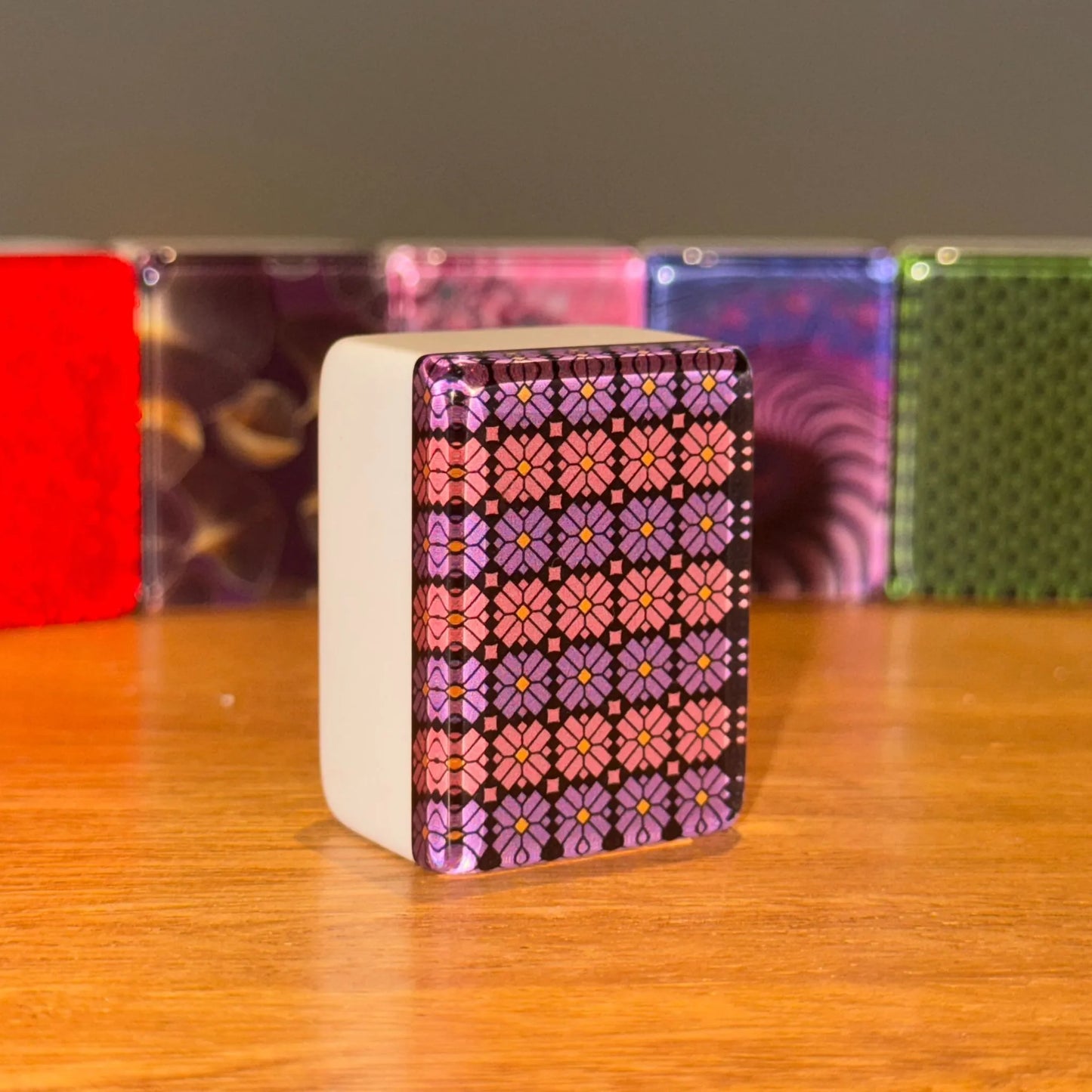 Violet mosaic 36mm automatic mahjong tile with geometric patterned face on wooden surface

